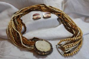 lot 42 image: Jewelry Signed Celia Sebiri (American, 1913-2006) torsade mixed material bead (wood, polished agate, brass) necklace with petrified wood pendant. Signed in script Celia Sebiri. Also includes mosaic bone and wood inlaid clip earrings. (also signed)