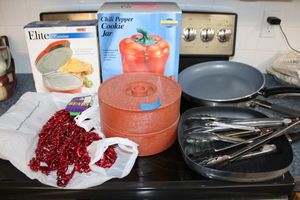 lot 151 image: Chili Pepper themed lot cookie jar, beads, tortilla warmers, and skillets