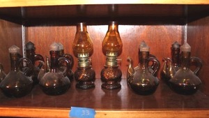 lot 33 image: Amber glass Oil and Vinegar jars teapot style - set of 8, and 2 amber glass small hurricane lamps