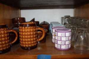 lot 281 image: Brown pottery dishes, coffee mugs, and glassware