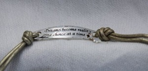 lot 335 image: Sterling Silver medallion Dreams become reality one day at a time on double silver color leather 22L chokernecklace with ball bead button closure. Marked 925 on reverse of medallion. Medallion 1.25L with star dangle.