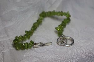 lot 414 image: Sterling Silver Peridot chip bead PEACE charm bracelet. Peridot tested and has chromite and fried egg inclusions. Marked 925 on toggle clasp.