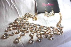 lot 446 image: Signed Zi Collection gold finish and faceted crystal bib style statement necklace with matching ear wire dangle earrings. Has logo hang tag. Lobster clasp. 18L. Earrings about 2.5L