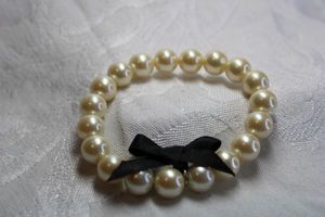 lot 464 image: Classic timeless faux pearl stretch bracelet with black bow.