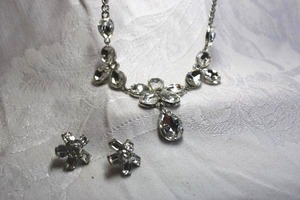 lot 484 image: Faceted tear drop glass crystal necklace with silver finish cable chain yoke. Lobster clasp. 16L with 3 extender. Also includes a pair of faceted prong set crystal poststud earrings in star form.