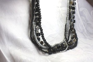 lot 511 image: Multi strand mixed material black and grey necklace. Includes black and grey wood beads, free form iridescent shell beads and black glass micro beads. 16L with 2 extender and cone connectors.