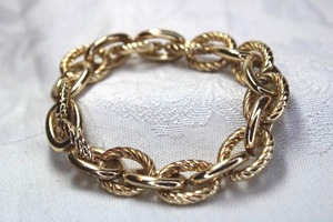 lot 514 image: Gold finish textured and solid heavy oval metal link stretch bracelet. Minor wear marks not easily seen.