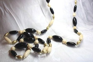 lot 515 image: Black, cream and gold oval tube acrylic bead continuous necklace with gold ball spacers, 48L