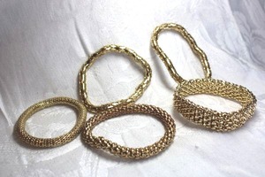 lot 525 image: (5) High polish swedged flexible gold finish stretch bracelets.