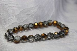 lot 442 image: Metallic color holiday sparkle faceted clear and gold variant glass bead stretch bracelet.
