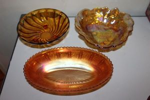 lot 132 image: Iridescent Beaded Block Depression Glass Celery dish, Amber Carnival Glass Loganberry Raised Berries Leaves Candy dish, and Footed Amber Swirl bowl