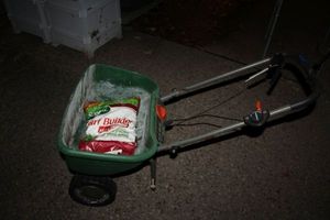 lot 564 image: Yard broadcast spreader with unopened bag of Turf Builder