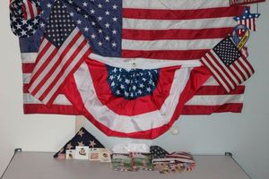 lot 62 image: American Flags and More. 3ftx5ft Flag, Banner, Wind Socks, God Bless America sign, Label and Hat Pins, Necklaces, Tie Pins and More