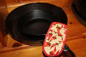 lot 265 image: Two Cast Iron Skillets with a handle mitten. 10-12in Lodge Brand Skillet approx. 2-3 Inches Deep and Smaller 4in (approx.) Cast