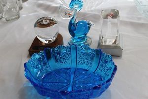 lot 130 image: Colbalt Blue Daisy Button Basket, Clear Glass Apple , Colbalt Blue Murano Pelican with Fish in Mouth and Glass Block with Statute of Liberty Lasered Into it and Lighted Display Base