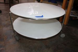 lot 54 image: 30 Round glass top table. Rolling with 2 tiers and chrome frame.