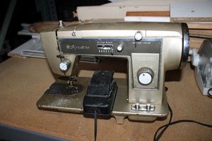 lot 128 image: Vintage Signature sewing machine and foot pedal. Model UHT J285E. J-C12. Made for sewing table.