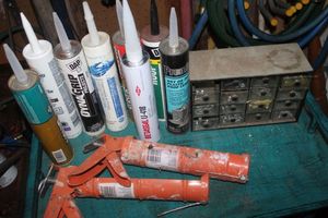 lot 406 image: Selection od Caulk and Adhesives, 2 Caulk Guns, and Hardware Cubby with Contents