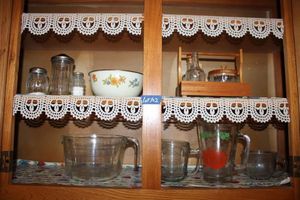 lot 102 image: Vintage measuring cups, juice pitcher, condiment caddy, and shakers
