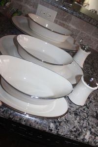 lot 247 image: Lenox Moon spun Oval Serving Platters 14in and 16in, Oval Serving Bowls 9in and 10in and Gravy Boat with attached under plate. and Salt and Pepper Mill (not Moon spun) Ivory and Platinum Rim (7 Total Pieces)