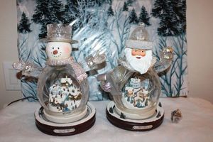 lot 15 image: Pair of Thomas Kincaid animated village globes. Both light up and have train that circles.