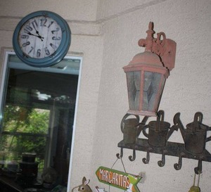 lot 130 image: Home decor wall clock, watering can metal wall hook, yellow birdhouse, and wood sign