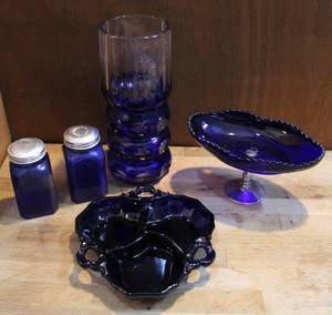 lot 15 image: mixed lot of blue glass held to light so you could see the blue salt and pepper shakers and vase and more