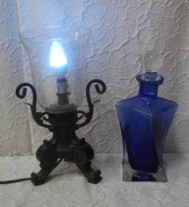 lot 196 image: This is a hand blown decanter featuring a striking cobalt blue color and a unique swirling pattern within the glass, which adds to its artistic appeal. And a light with a blue light