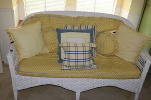 lot 1 image: Wicker loveseat with yellow and blue pillows. 59W x 20D x 34.5H