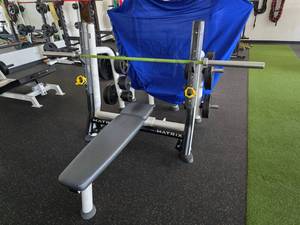lot 116 image: Matrix Magnum Series Breaker Olympic Flat Bench w Pivoting Uprights, Plate Weights & American 20KG Bar (Bar Alone Costs $580).  Weights Include 45lb (Qty 4), 25lb (Qty 4), 10lb (Qty 6), 5lb (Qty 8) &2.5lb (Qty 10)