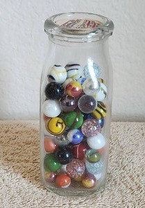 lot 9 image: Selection of vintage marbles in a vintage glass milk jug