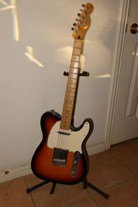 lot 8 image: Fender electric guitar with stand and hard case. Includes guitar tuner and guitar picks.