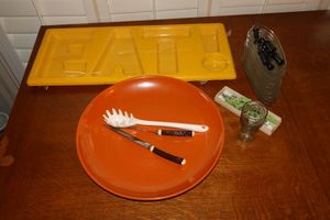 lot 13 image: Large orange pottery bowl with vintage carving set, Small Coke glass, ceramic corn-on-the-cob holders and unopened yellow EAT serving tray