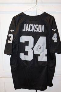 lot 128 image: Bo Jackson #34 jersey (has signature- dont know if its printed or authentic, please preview). Still has tags.