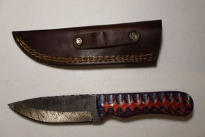 lot 244 image: 3.75 blade hunting knife with leather sheath.  Blue and red wood grain handle.