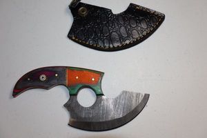 lot 248 image: 5 blade Ulu knife with finger hole and  leather sheath.  Orangegreen and greypink wood grain handle.