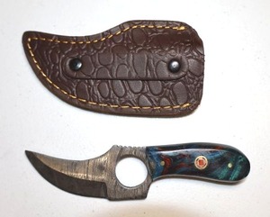 lot 253 image: 2.25 blade Skinner knife with finger hole.  Leather sheath.  Blue, red, and green resin handle.