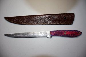 lot 263 image: 8.5 blade fillet knife with leather sheath.  Pink and blue wood tone handle.