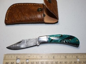 lot 13 image: Pocket knife with leather sheath.  Green and black resin handle.