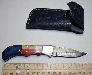 lot 14 image: Pocket knife with leather sheath.  Texas flag wood grain handle.