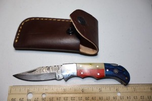 lot 15 image: Pocket knife with leather sheath.  Texas flag wood grain handle.