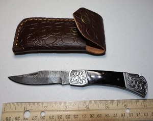 lot 20 image: Folding Pocket knife with leather sheath.  Black resin handle.