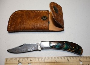 lot 24 image: Folding Pocket knife with leather sheath.  Green and gold resin handle.