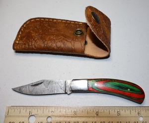 lot 25 image: Folding Pocket knife with leather sheath.  Red and green wood grain handle.
