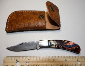 lot 26 image: Folding Pocket knife with leather sheath.  Multi colored resin handle.
