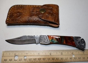 lot 27 image: Folding Pocket knife with leather sheath.  Multi colored resin handle.