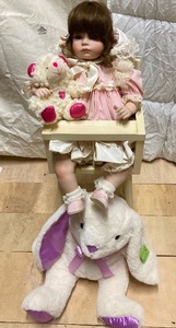 lot 284 image: VTG Doll in a Cream-Colored, High Chair with Bear Motif. She has a stuffed teddy in her lap and has a large Bunny By Her Chair