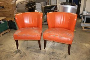 lot 384 image: Two orange leather arm chairs as shown