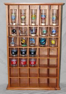 lot 112 image: wooden shot glass display case. With a hand full of shot glasses