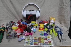 lot 317 image: mixed lot of small toys and accessories, including action figures, stuffed animals, a toy truck, stickers, and a pair of white over-ear headphones.